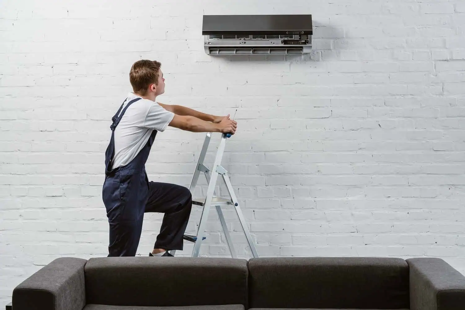 Technician servicing wall-mounted air conditioning unit.